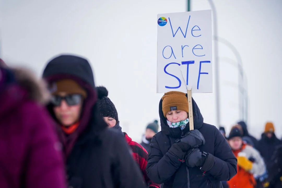A woman holds a sign while walking at a demonstration site during a province-wide, one-day strike organized by the members of Saskatchewan Teachers’ Federation in Saskatoon on Jan. 22, 2024. (The Canadian Press/Heywood Yu)