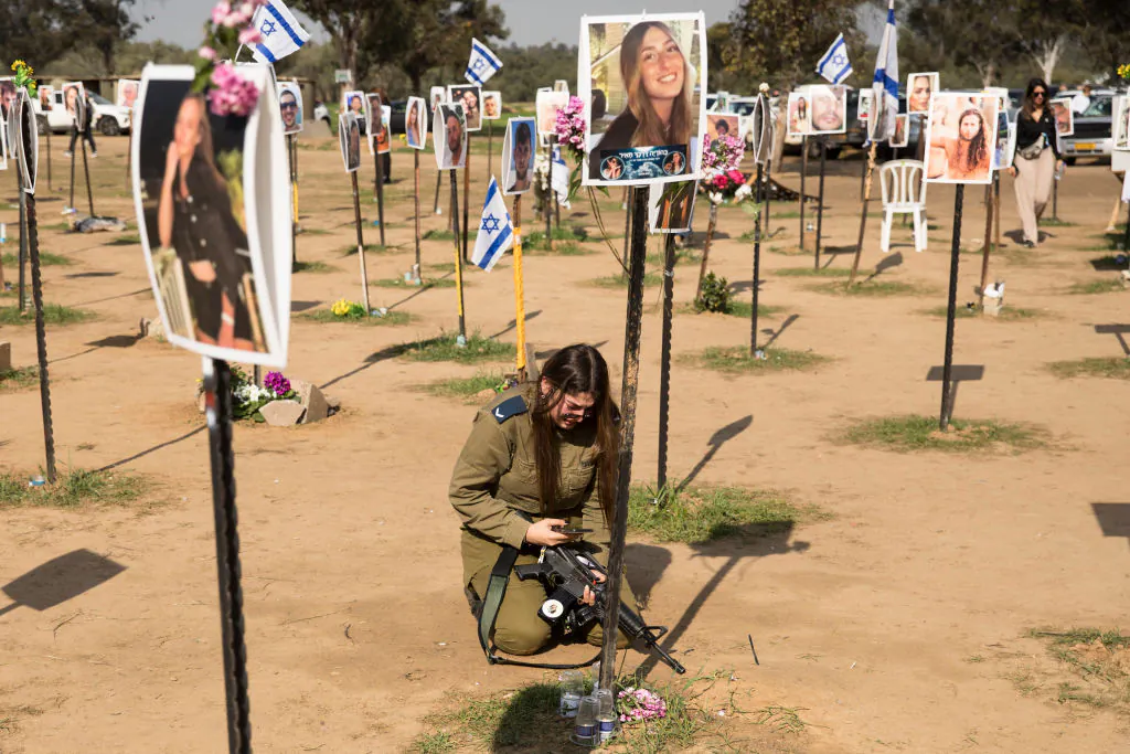 A soldier mourns near a photo of a deceased relative at the Nova music festival site on January 5, 2024 in Re'im, Israel. Approximately 40 hostages were taken from the Nova music festival site during Hamas's Oct. 7 attack, alongside the 364 who were killed, according to Israeli authorities.  (Photo by Amir Levy/Getty Images)