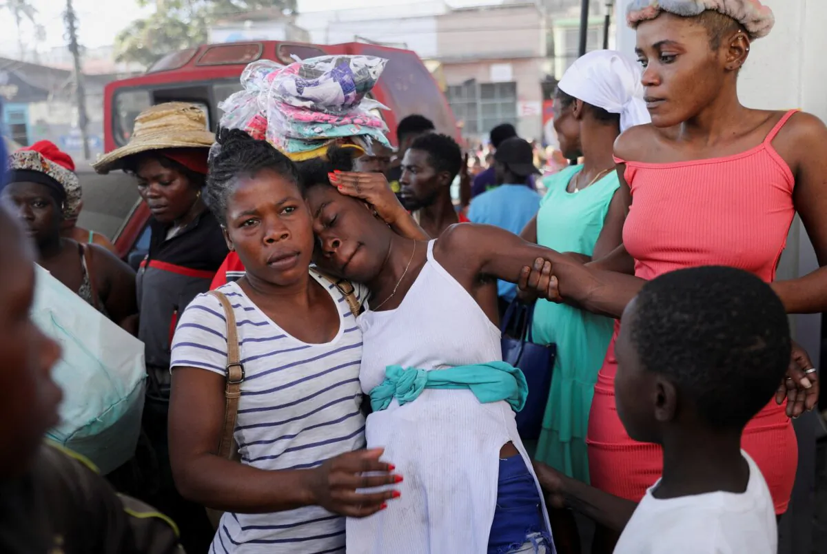 A woman is comforted by others at a crime scene where the bodies of several people, who had been shot dead earlier in the morning amid an escalation in gang violence, were being removed by an ambulance in Port-au-Prince, Haiti, on March 18, 2024. (Ralph Tedy Erol/Reuters)