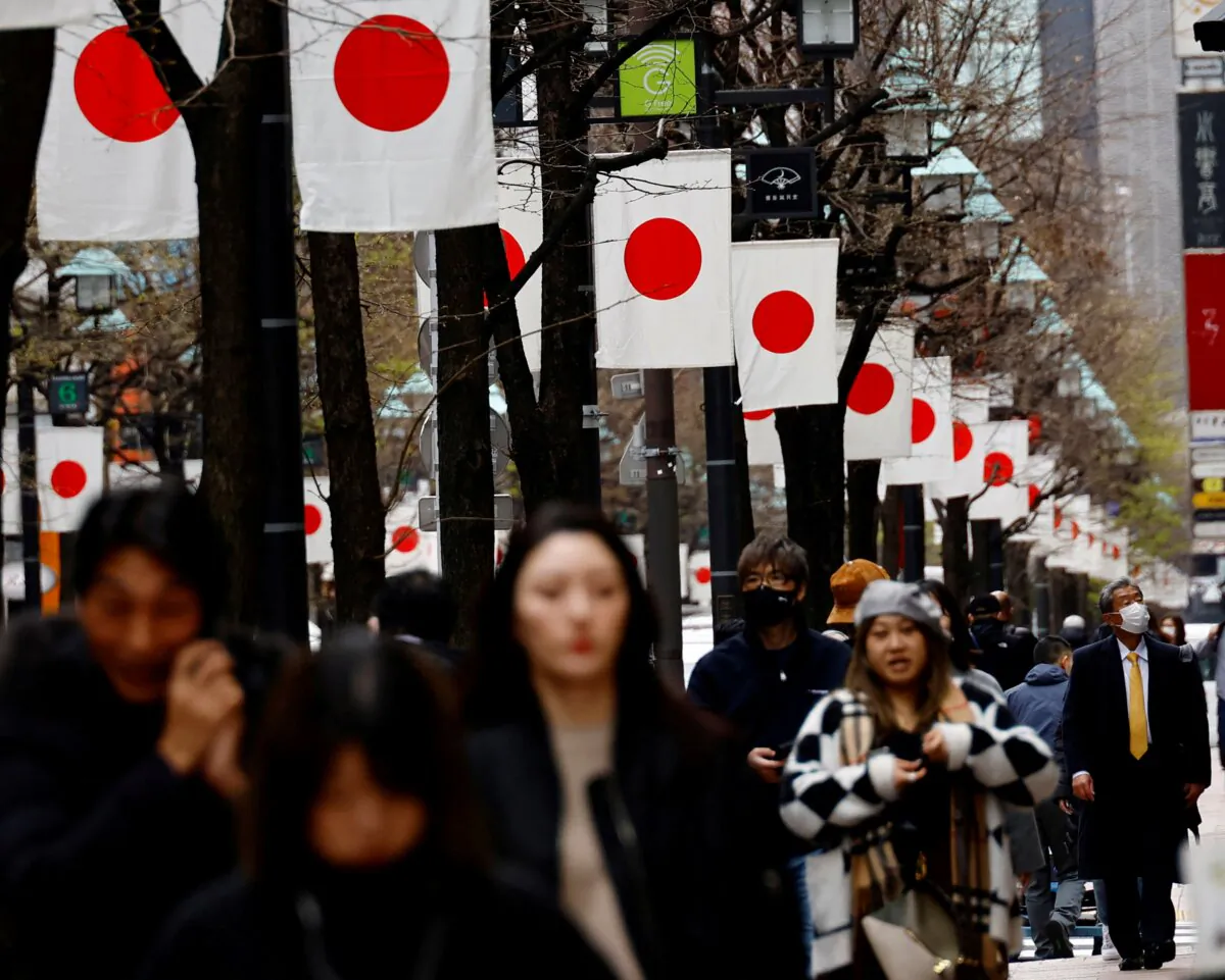 People walk past Japan’s national flags in a shopping district in Tokyo on March 19, 2024. (Kim Kyung-Hoon/Reuters)