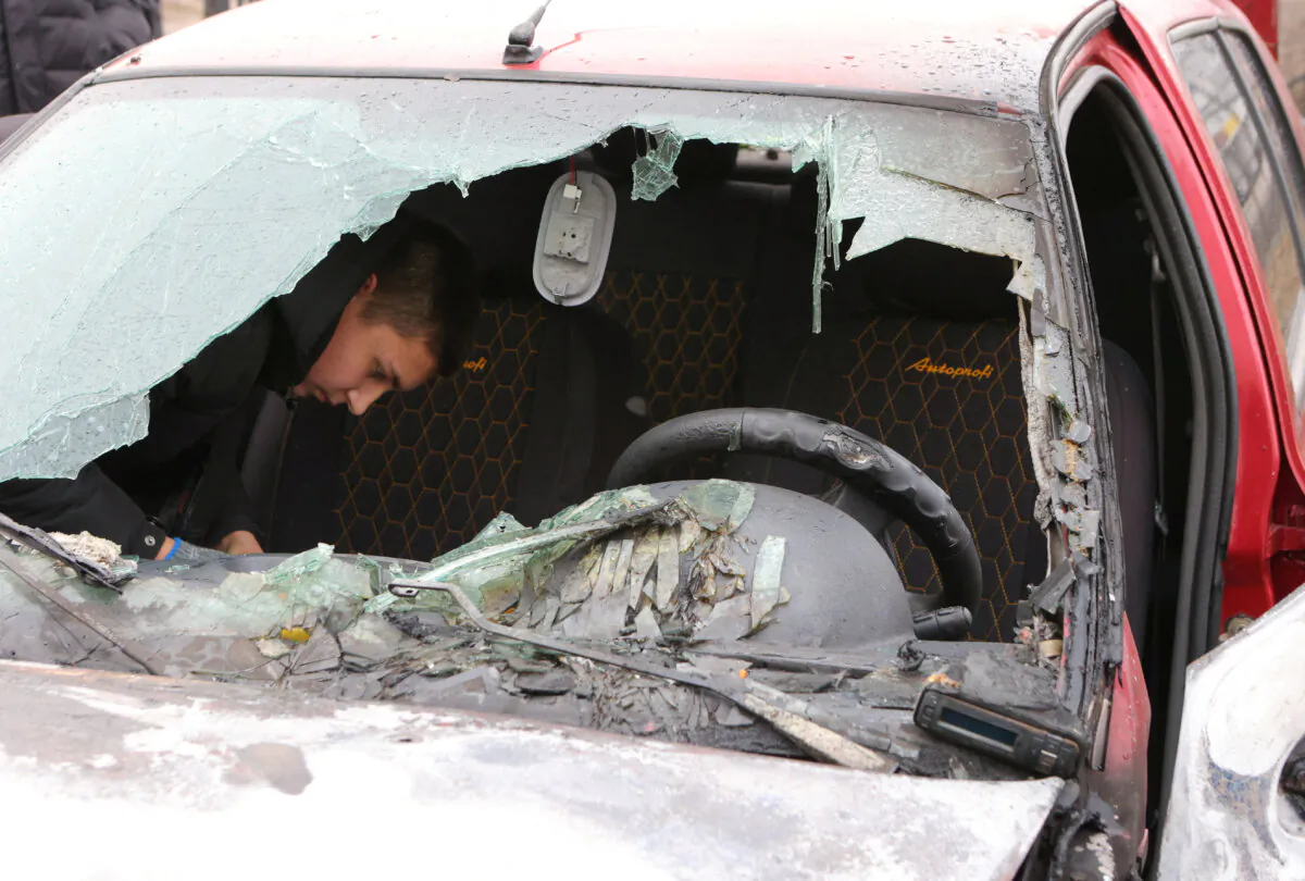 A local resident inspects a damaged car hit by a Ukrainian shelling in the settlement of Razumnoe in the Belgorod Region, Russia, on March 19, 2024. (Stringer/Reuters)
