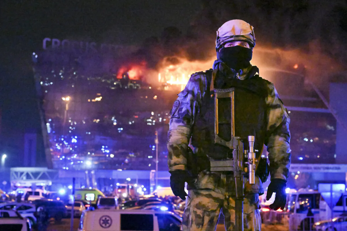 A Russian Rosguardia (National Guard) servicemen secures an area as a massive blaze seen over the Crocus City Hall on the western edge of Moscow, Russia, on March 22, 2024. (Dmitry Serebryakov/AP Photo)