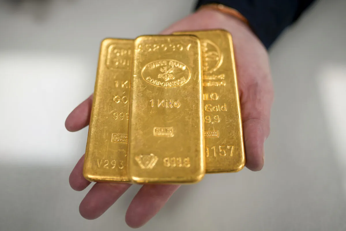 A gold dealer poses with three 1kg gold bullion bars in Birmingham, England, on Dec. 13, 2023. (Christopher Furlong/Getty Images)