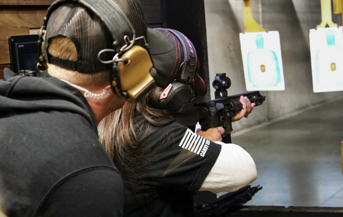An attendee of National Women's Range Day shoots a semi-automatic rifle at the Texas Gun Experience indoor shooting range as a range officer/instructor observes on March 9, 2024. (Michael Clements/The Epoch Times)