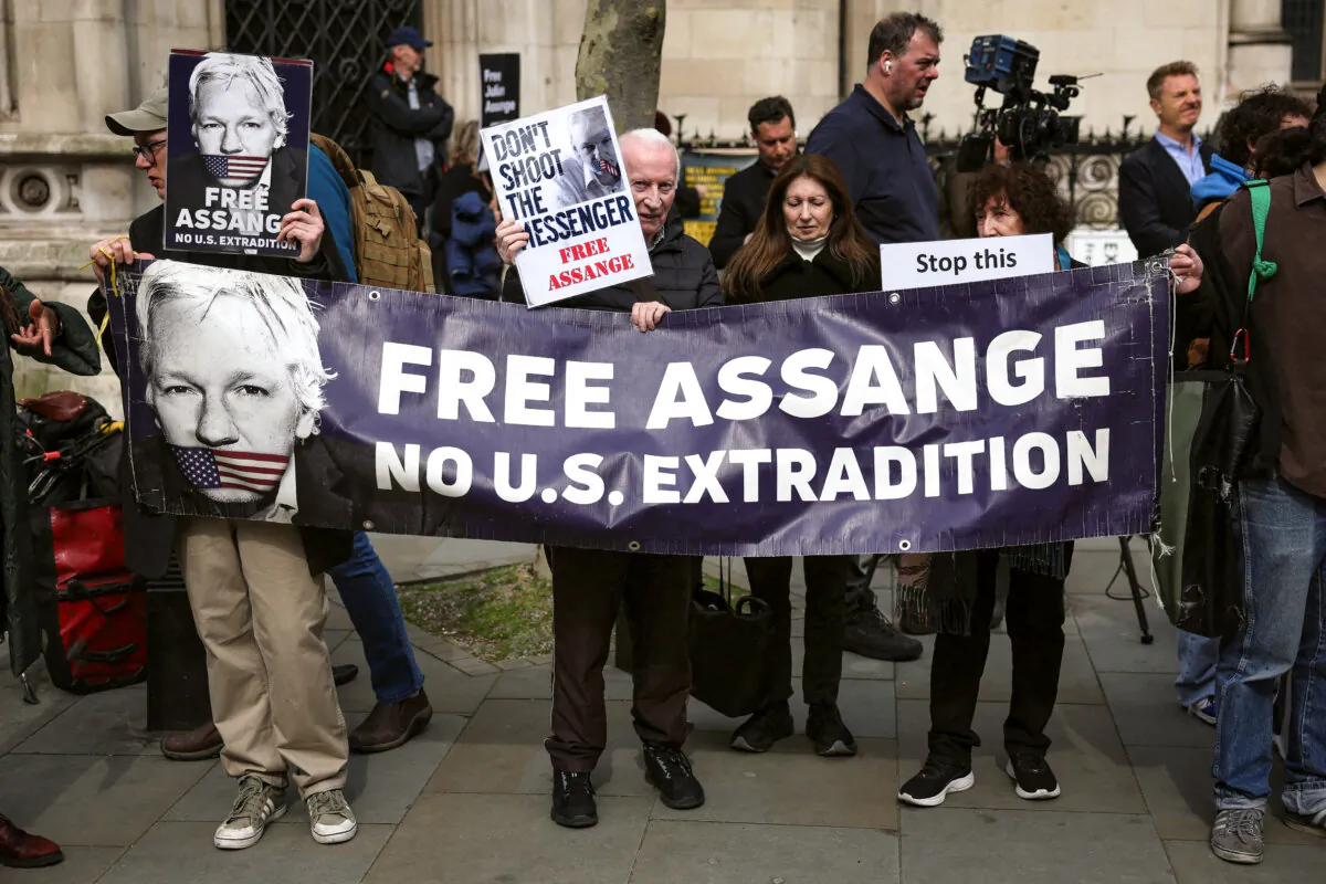 Supporters of WikiLeaks founder Julian Assange hold a banner and placards outside the Royal Courts of Justice, Britain's High Court, in central London on March 26, 2024. (Daniel Leal/AFP via Getty Images)