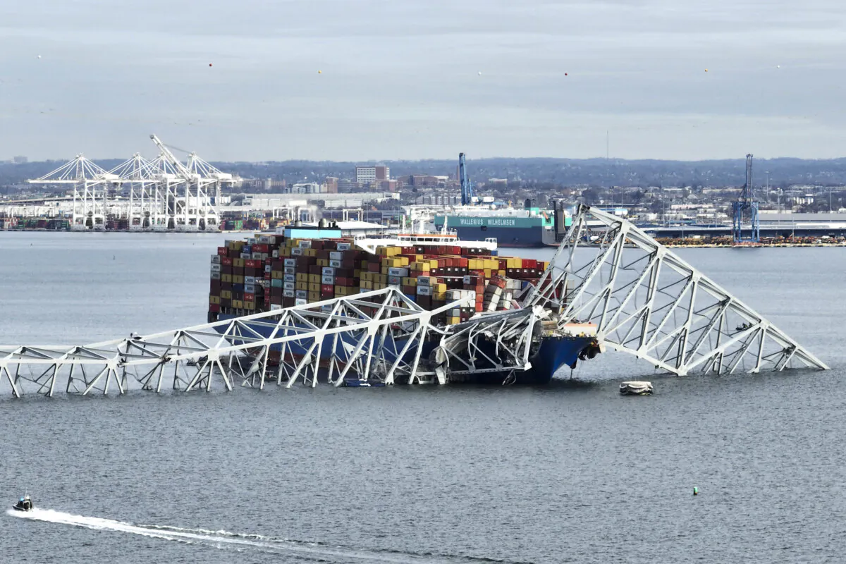 The steel frame of the Francis Scott Key Bridge sits on top of a container ship after the bridge collapsed, in Baltimore on March 26, 2024. (Jim Watson/AFP via Getty Images)