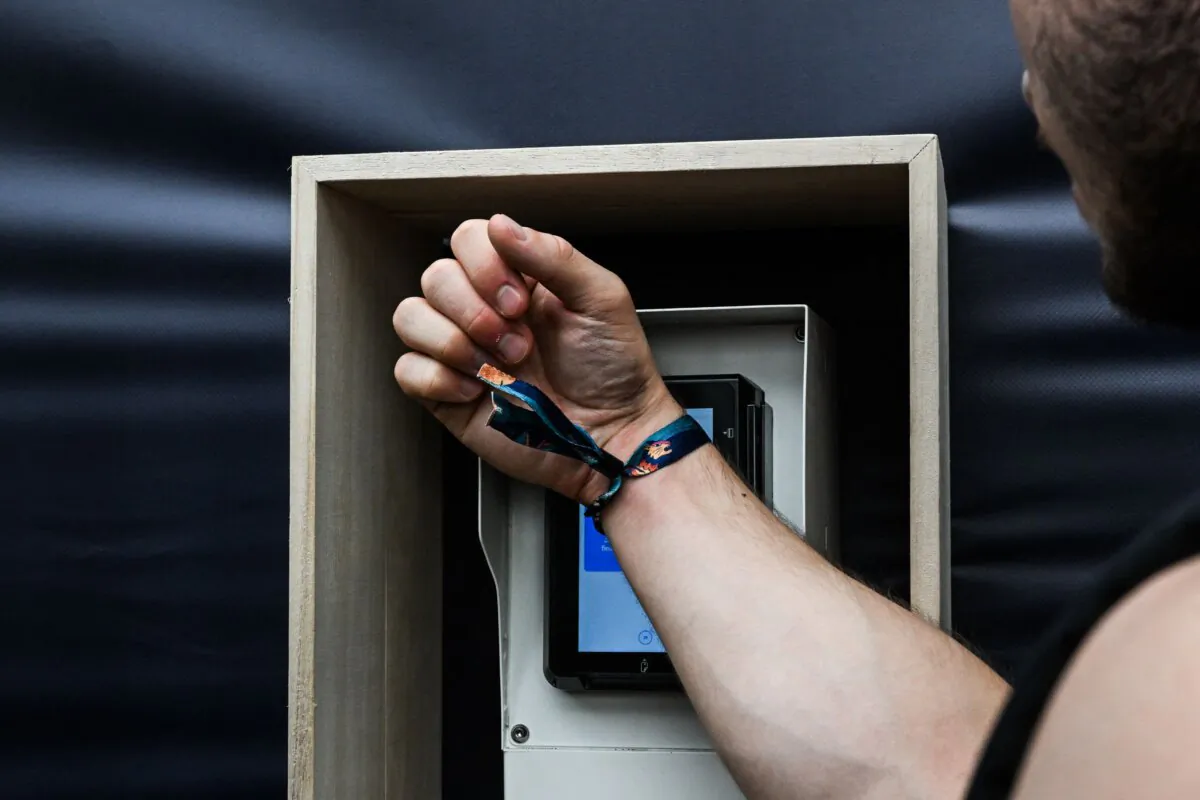 A festivalgoer sets his cashless account and charge his wristband with a cashless recharging machine during the Rock en Seine Festival in Saint-Cloud, southwestern Paris, on Aug. 23, 2023. (Anna Kurth/AFP via Getty Images)