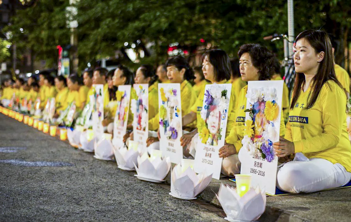 Falun Gong practitioners participate in a candlelight vigil, holding photos of fellow adherents who have died as a result of persecution in China, in front of the Chinese Consulate in Toronto on July 13, 2019. (The Epoch Times)