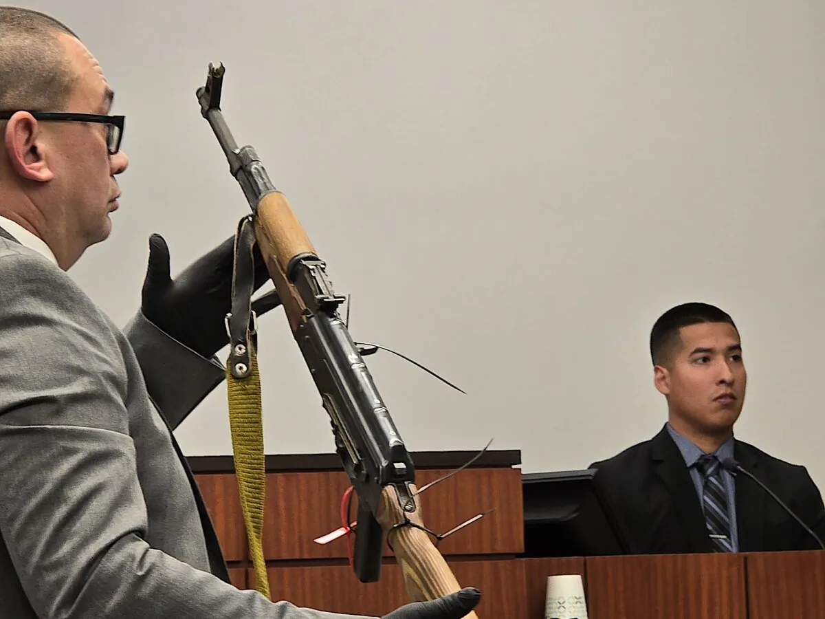 A Santa Cruz County detective (L) holds the AK-47 rifle George Alan Kelly allegedly used to fatally shoot an illegal immigrant. Giving testimony is Santa Cruz County Sheriff's Deputy David Monreal (R), in Santa Cruz County Superior Court in Nogales, Ariz., on March 28, 2024. (Allan Stein/The Epoch Times)