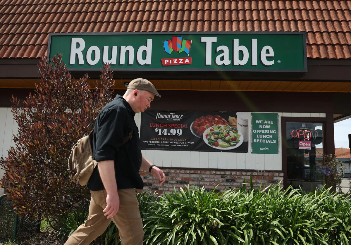 A sign is posted on the exterior of a Round Table pizza restaurant in Albany, Calif., on March 25, 2024. California fast food restaurants are laying off some staff and reducing hours for other workers as they look to cut costs ahead of a California state law that will raise the hourly wage of fast food workers to $20 an hour beginning on April 1. (Justin Sullivan/Getty Images)