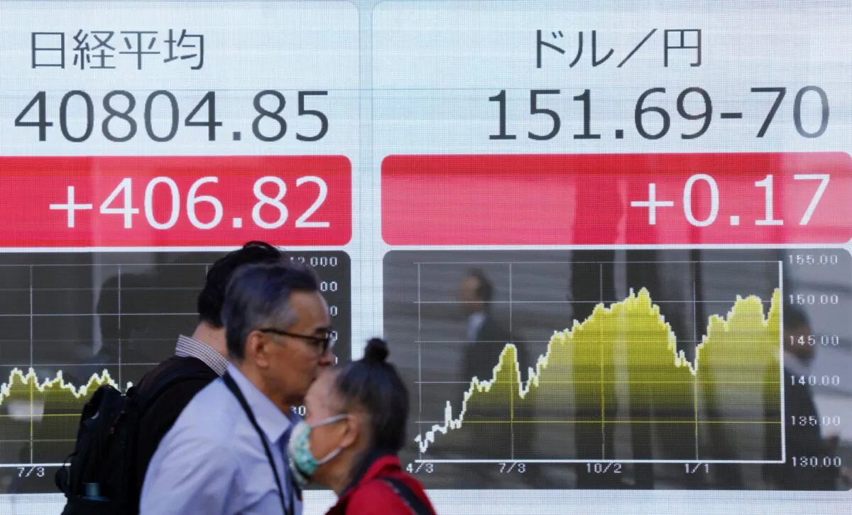 People walk past an electronic board showing a share price of the Nikkei index of the Tokyo Stock Exchange (L) and the rate of the Japanese yen versus the US dollar (R) along a street in Tokyo, on March 27, 2024. (Kazuhiro Nogi/AFP via Getty Images)