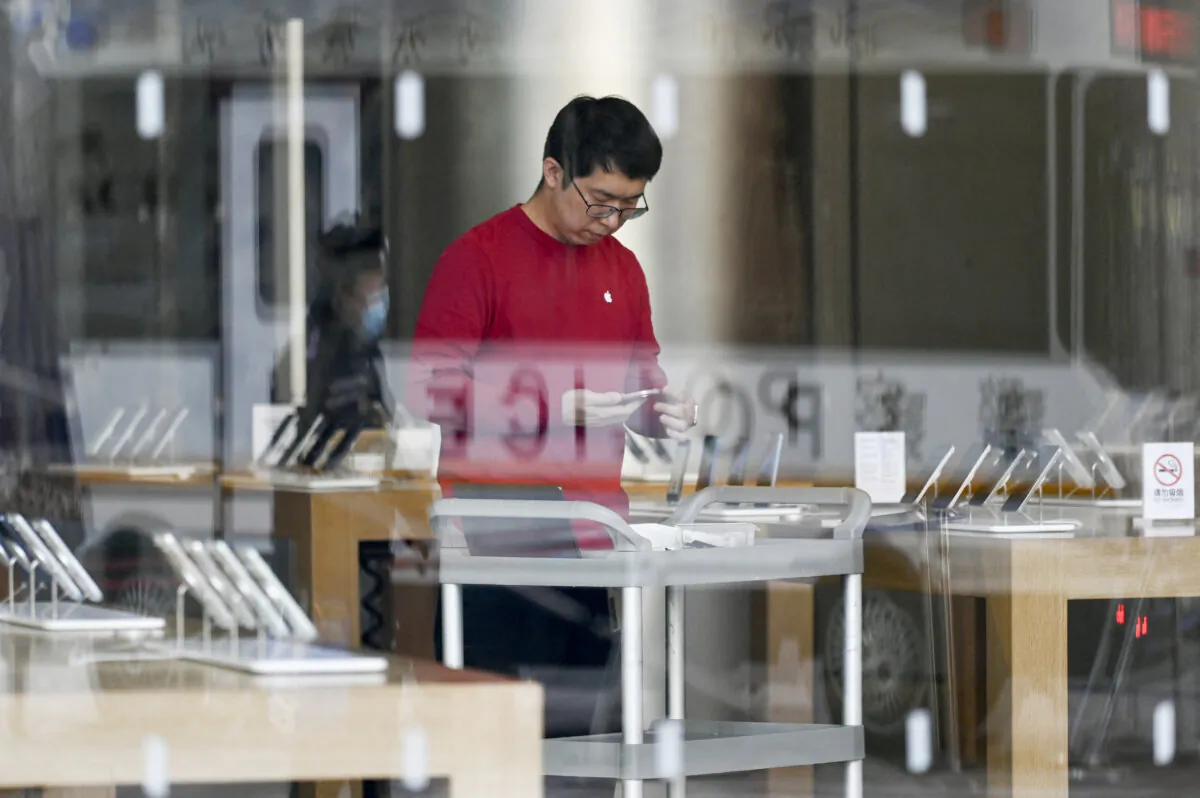 An Apple Store employee prepares for the opening of business in Beijing on Dec. 6, 2023. (Wang Zhao/AFP via Getty Images)