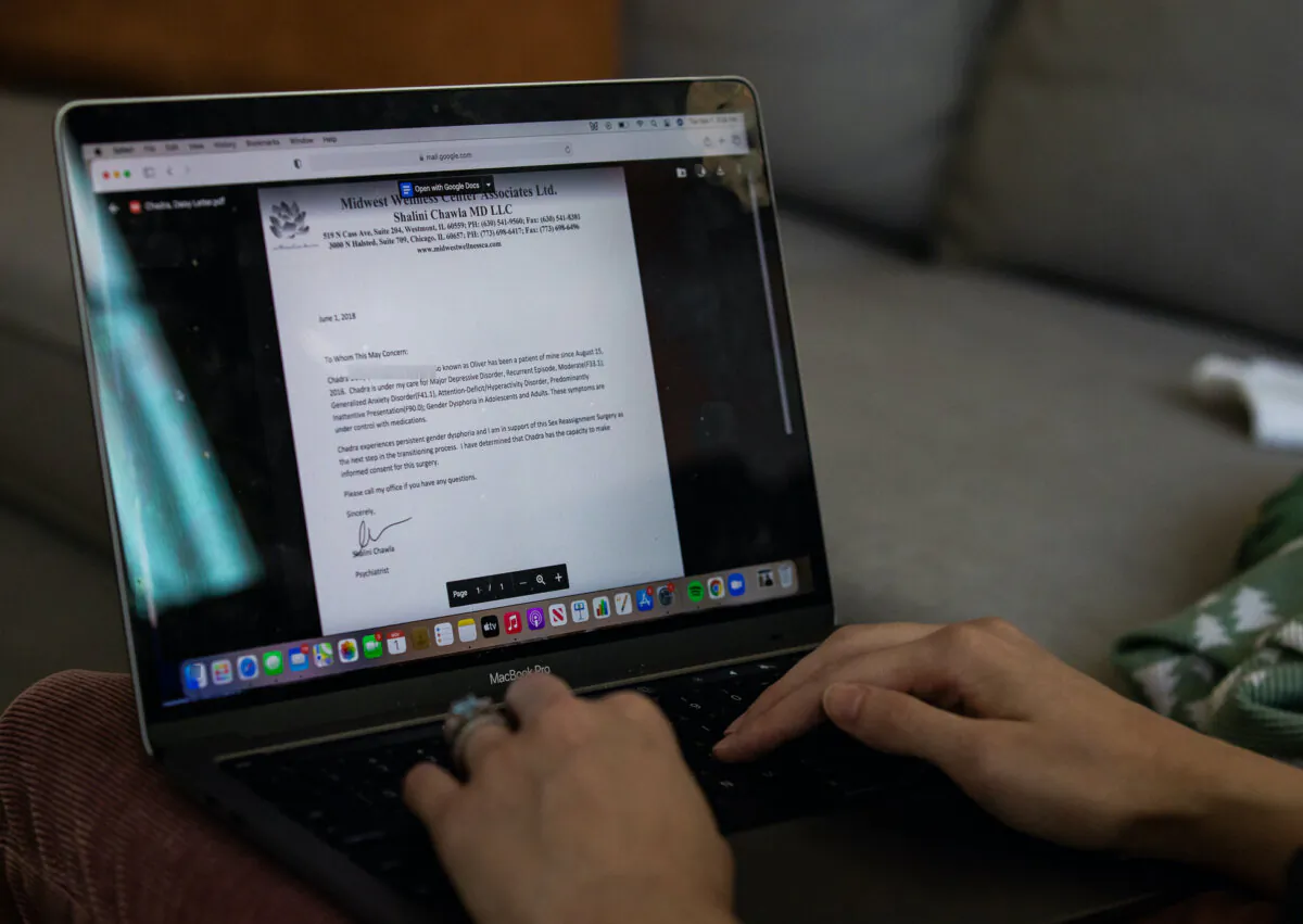 In a file photo, a detransitioner looks at a letter from her former doctor who authorized a double mastectomy for transitioning into a male, at her home on Nov. 1, 2022. The woman now regrets the procedure. (John Fredricks/The Epoch Times)