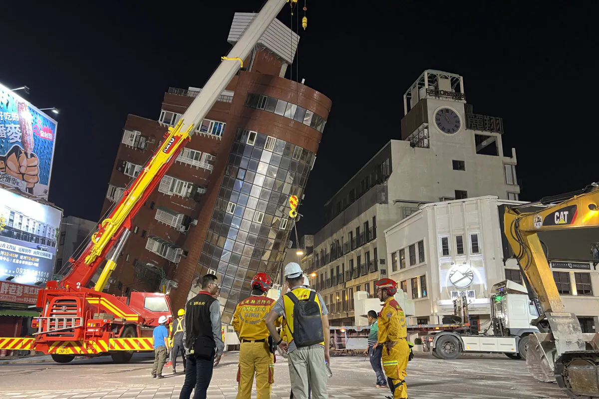 Rescue workers stand near the site of a leaning building in the aftermath of an earthquake in Hualien, eastern Taiwan on April 3, 2024. (The Canadian Press/AP Johnson Lai)