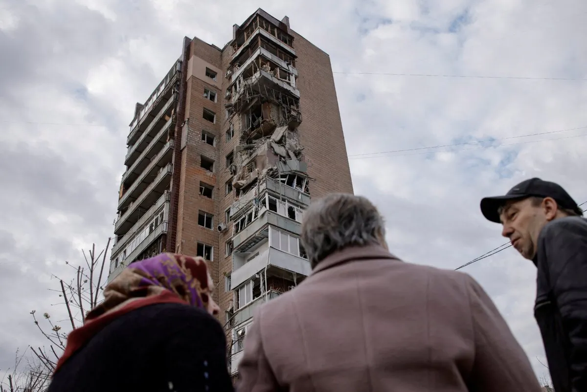 Residents stand in front of an apartment building hit by a Russian drone strike, amid Russia's attack on Ukraine, in Kharkiv, Ukraine, on April 4, 2024. (Yevhen Titov/Reuters)
