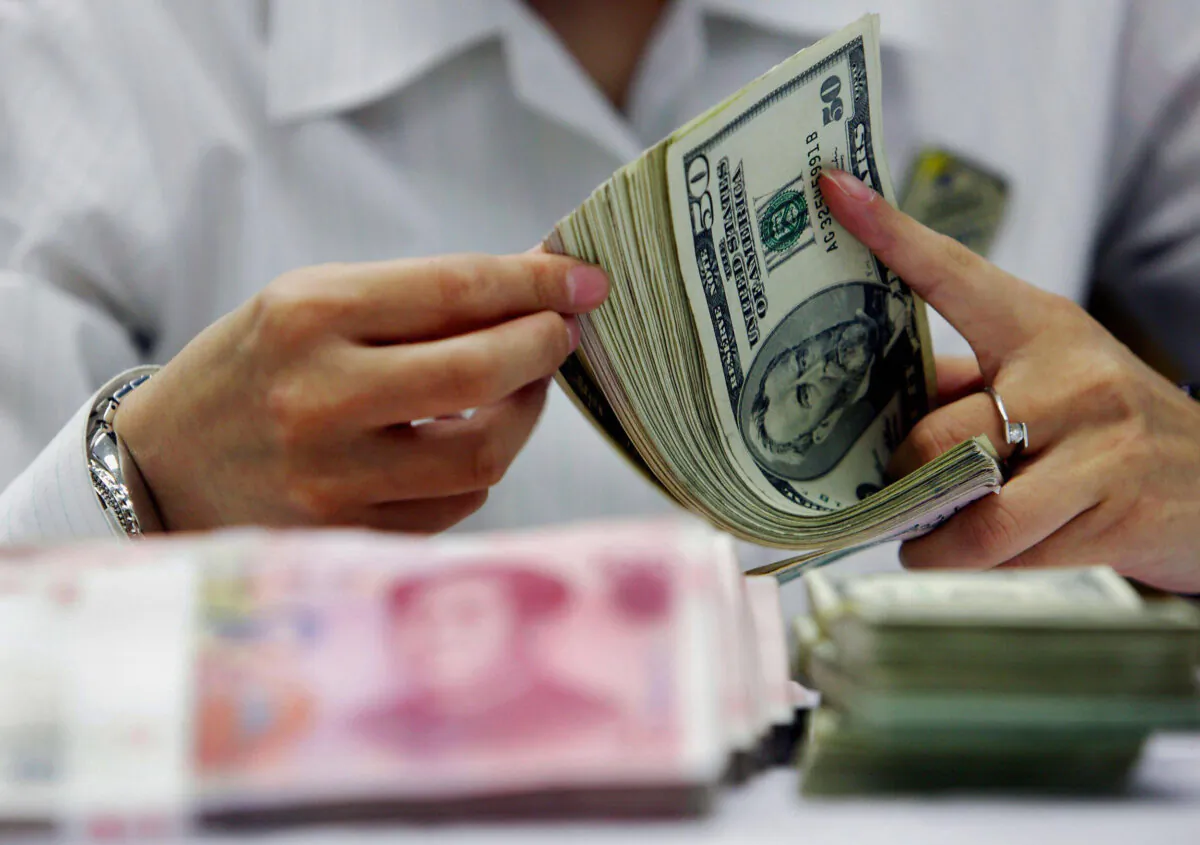 A bank teller counts the stack of Chinese yuan and U.S. dollars at a bank in Shanghai on July 22, 2005. (STR/AFP via Getty Images)
