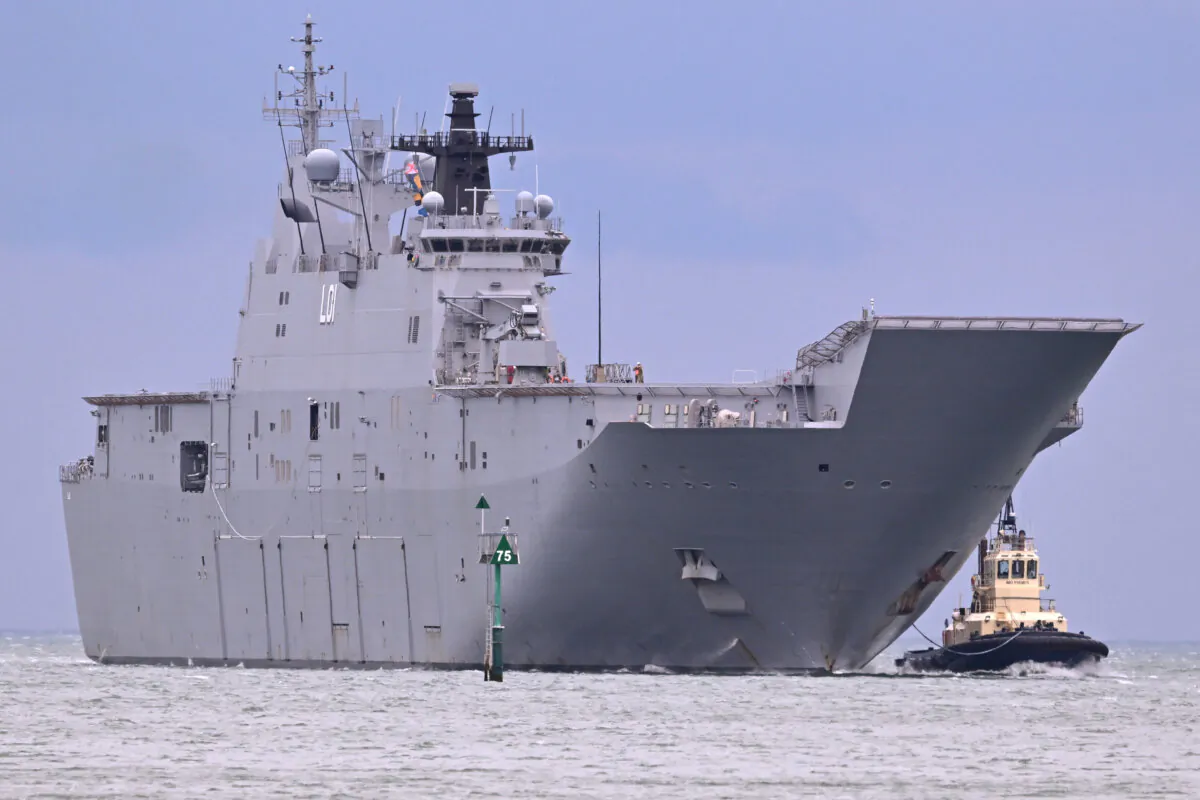 A tug escorts the HMAS Adelaide, a Royal Australian Navy (RAN) Canberra-class landing helicopter dock ship, as it docks at Station Pier in Melbourne on March 19, 2024. (William West/AFP via Getty Images)