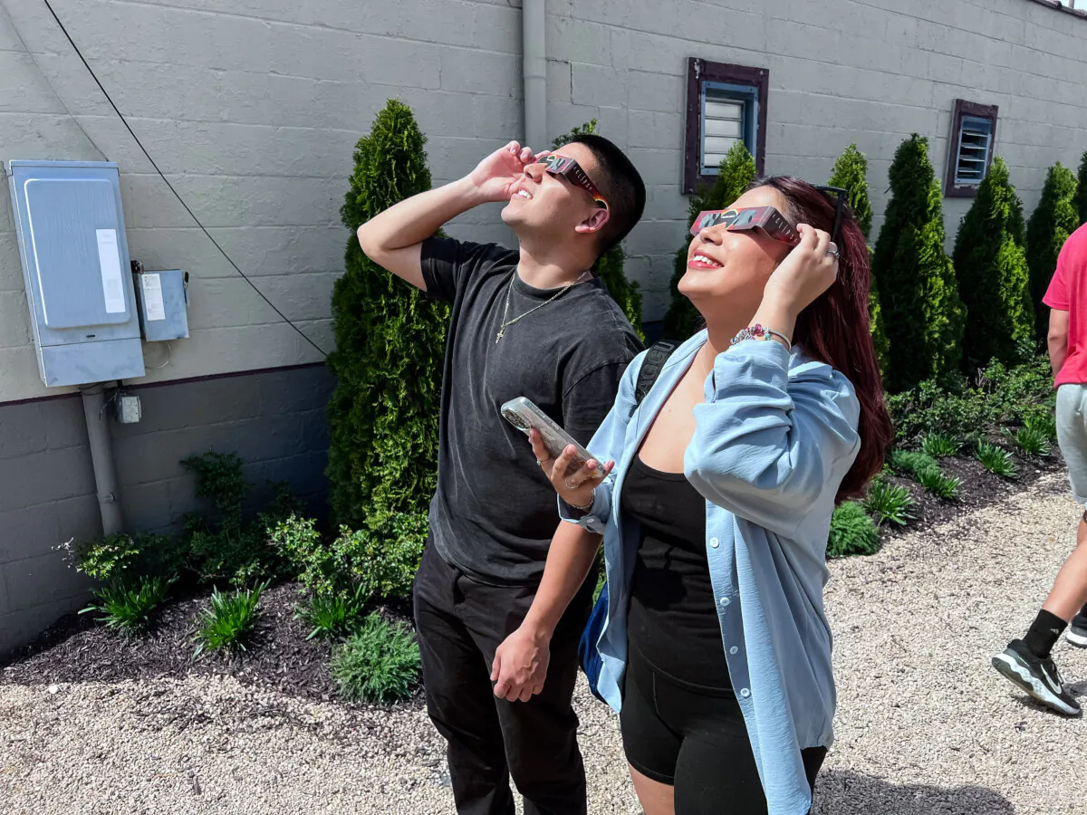 Two people view an early stage of the total solar eclipse in Indianapolis on April 8, 2024. (Lawrence Wilson/The Epoch Times)