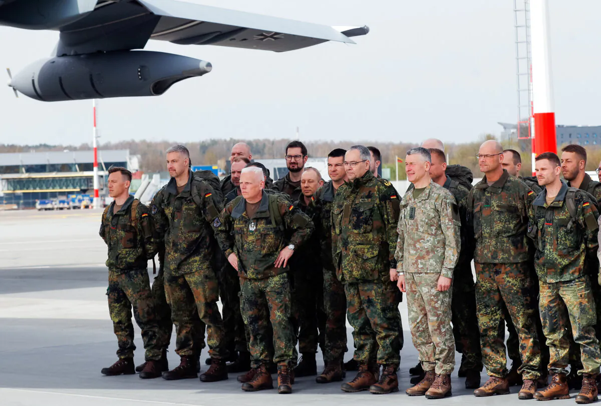 Lithuanian Chief of Defense Gen. Valdemaras Rupsys (light fatigues), and German Army Chief Lt. Gen. Alfons Mais (left of Gen. Rupsys) pose with German Bundeswehr soldiers of the Headquarters initial command element of the Bundeswehr's 45th Brigade Lithuania at airport in Vilnius, Lithuania, on April 8, 2024. (AP Photo/Mindaugas Kulbis)