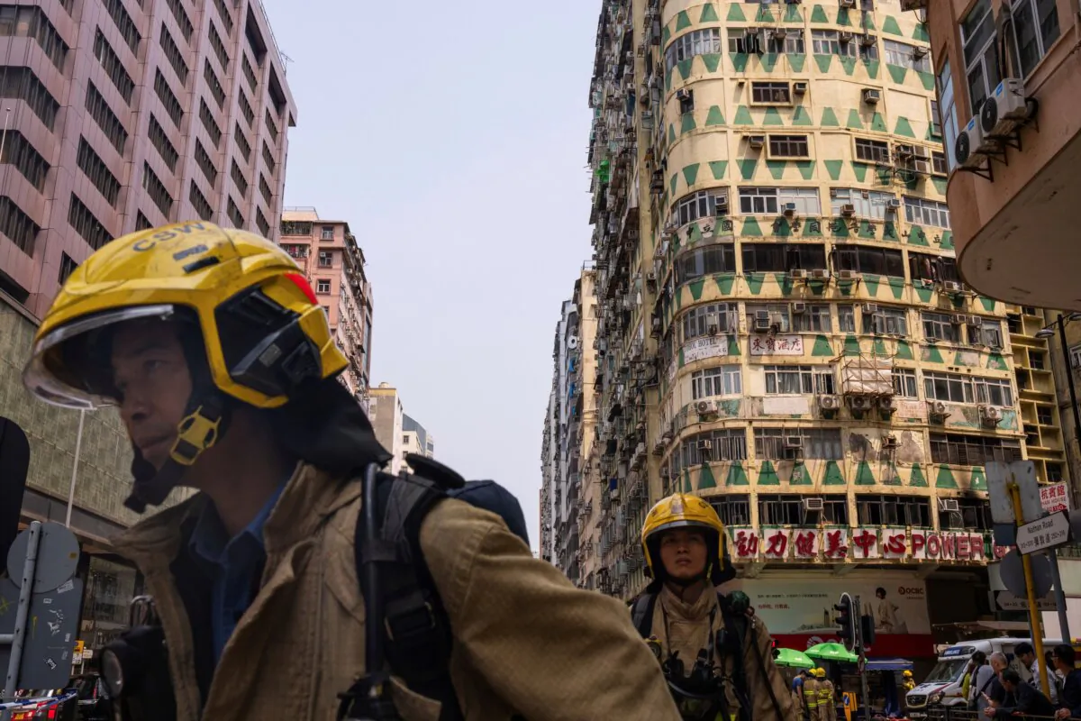 Firefighters walk past a building called New Lucky House where a fire started in Hong Kong on April 10, 2024. (Louise Delmotte/AP Photo)