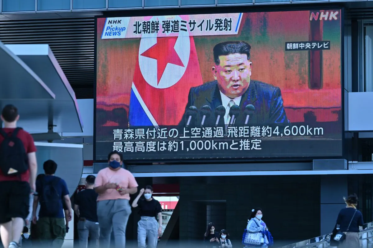 Pedestrians walk under a large video screen showing images of North Korea's leader Kim Jong Un during a news update in Tokyo on Oct. 4, 2022, after North Korea launched a missile early in the day which prompted an evacuation alert when it flew over northeastern Japan. (Richard A. Brooks/AFP via Getty Images)