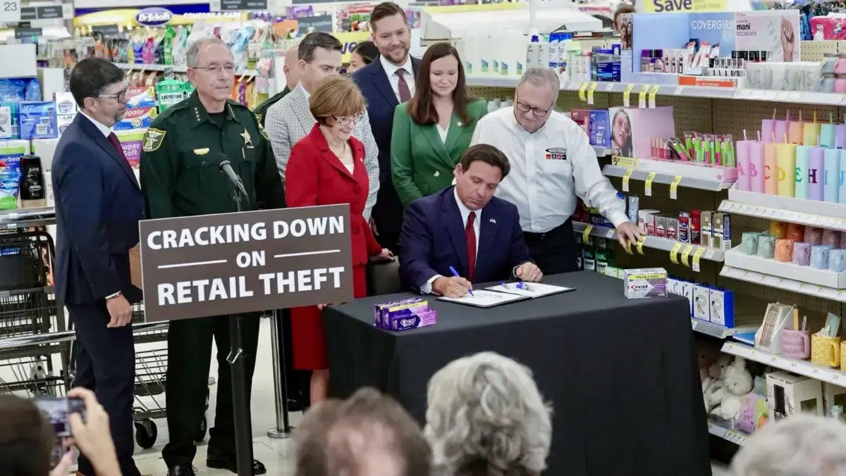 Florida Gov. Ron DeSantis signs into law tougher penalties for theft during a press conference with state Attorney General Ashley Moody (3rd R) at a Walgreens in Stuart, Fla., on April 9, 2024. (Courtesy of the Executive Office of the Florida Governor)