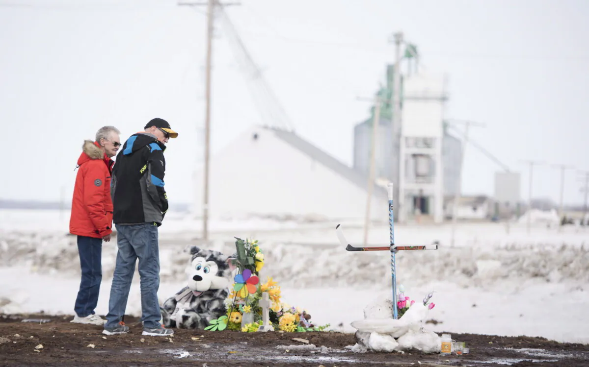 People pay their respects at a makeshift memorial near Tisdale, Sask., for the Humboldt Broncos hockey players on April, 9, 2018.  (The Canadian Press/Jonathan Hayward)