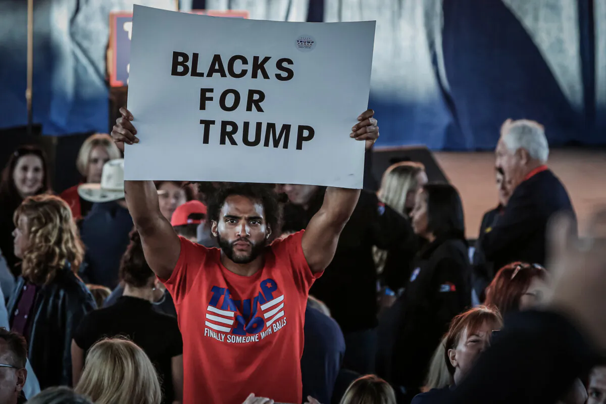 A man holds a "Blacks for Trump" sign as he waits to see Republican presidential nominee Donald Trump at an event in Sterling Heights, Mich., on Nov. 6, 2016. (Jeff Kowalsky/AFP via Getty Images)
