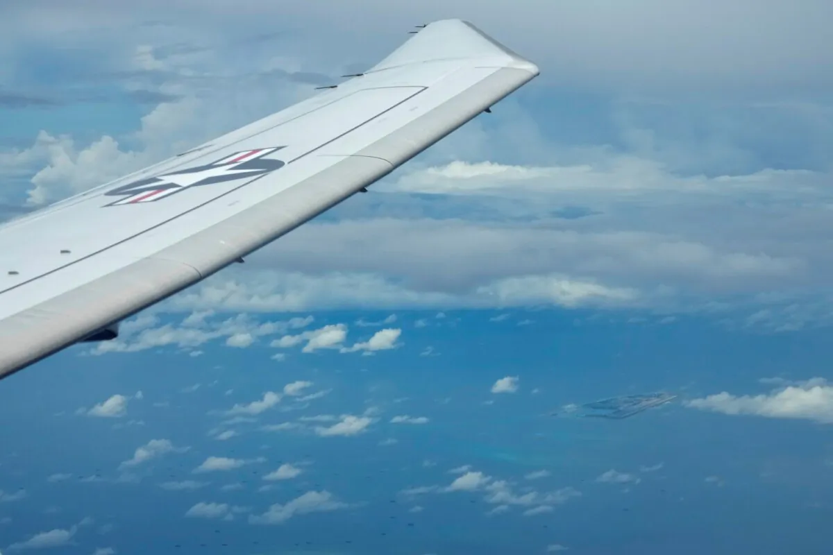 A U.S. P-8A Poseidon reconaissance plane flies near Chinese structures and buildings on the man-made Fiery Cross Reef at the Spratlys group of islands in the South China Sea, on March 20, 2022. (Aaron Favila/AP Photo)