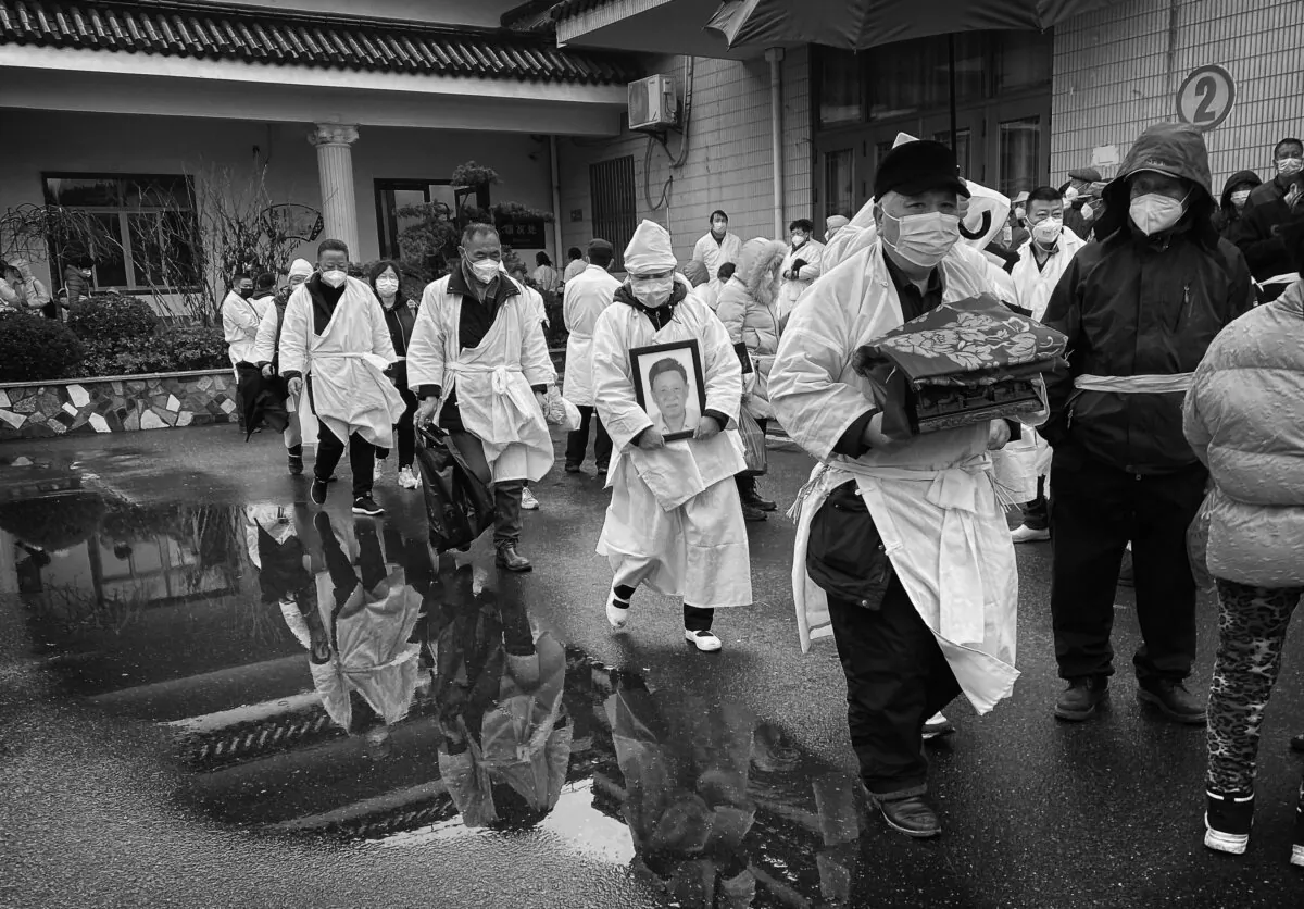 A mourner carries the cremated remains of a loved one as he and others wear traditional white funeral clothing, during a funeral in Shanghai, China, on Jan. 14, 2023. (Kevin Frayer/Getty Images)