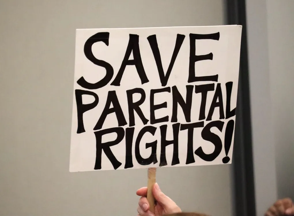 A parental rights advocate raises a sign during an Orange Unified School Board meeting in Orange, Calif., on Sept. 7, 2023. (Mei Lee/The Epoch Times)