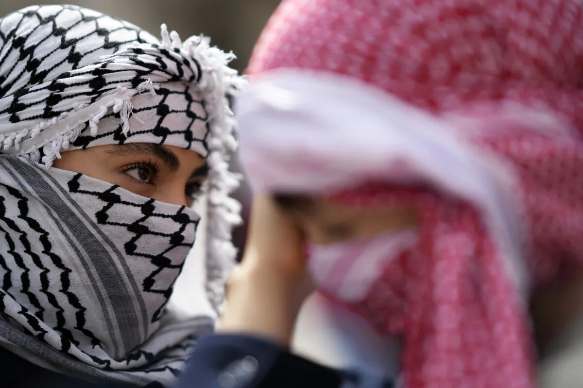 A young woman helps a child adjust his keffiyeh during a demonstration in Lisbon on April 7, 2024. (The Canadian Press/AP/Armando Franca)