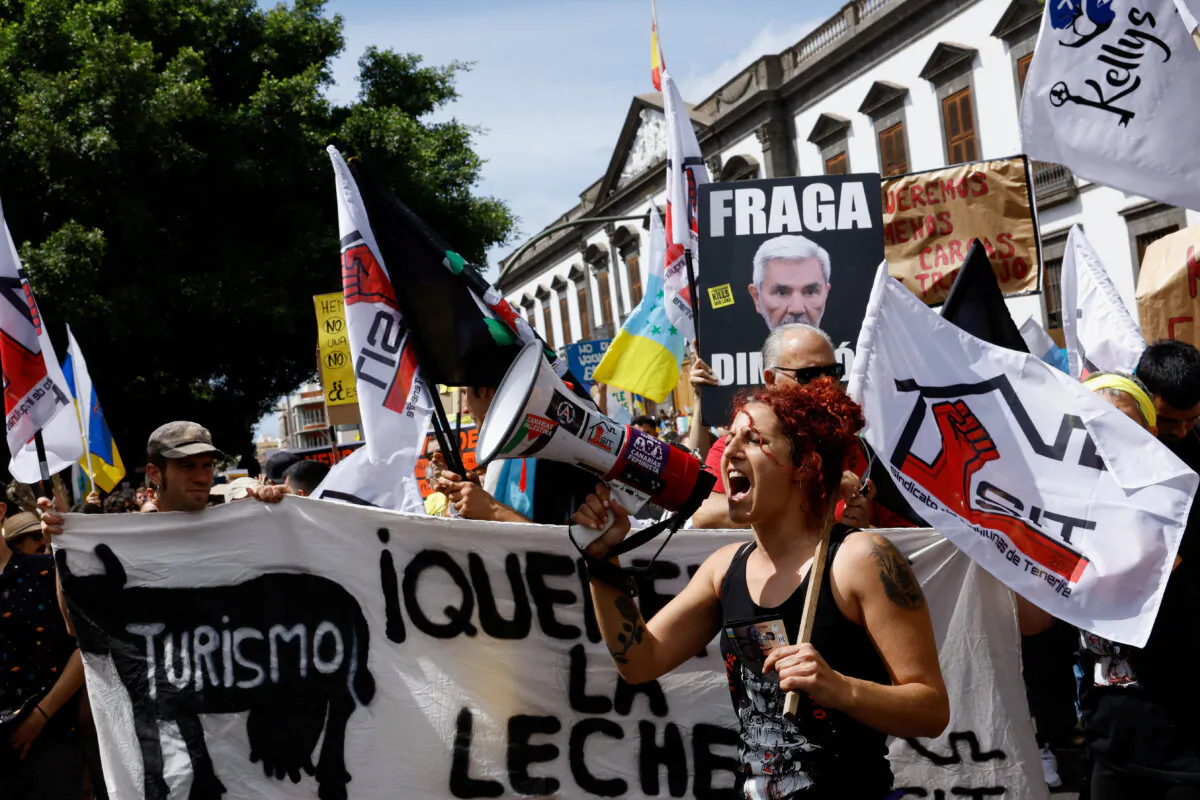 A woman uses a megaphone during a demonstration for a change in the tourism model in the Canary Islands, in Santa Cruz de Tenerife, Spain, on April 20, 2024. (Borja Suarez/Reuters)