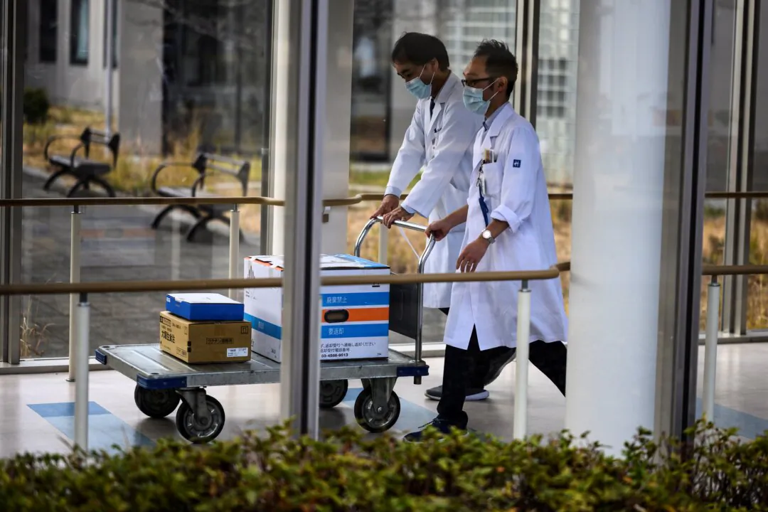 Medical workers push a trolley with boxes containing COVID-19 vaccines as Japan launches its inoculation campaign, at the Tokyo National Hospital in Kiyose, Tokyo prefecture, on Feb. 17, 2021. (Charly Triballeau/AFP via Getty Images)