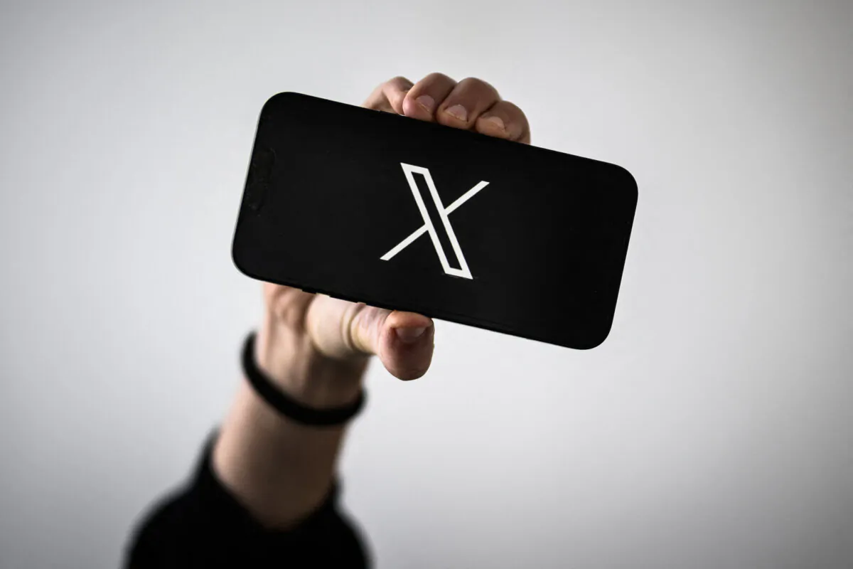 A woman holds a smartphone displaying the logo of US social network X (former Twitter), in Nantes, western France, on Nov. 29, 2023. (LOIC VENANCE/AFP via Getty Images)