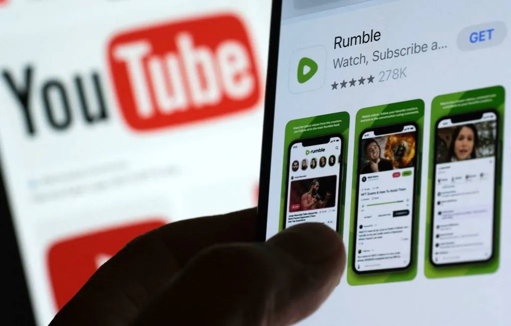 The Rumble app download page on a smartphone against a YouTube logo background in Los Angeles, on March 29, 2023. (Chris DelmasAFP via Getty Images)