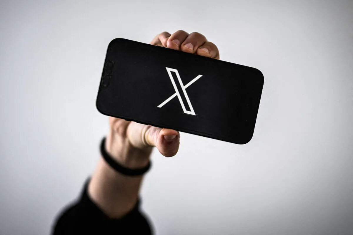 A woman holds a smartphone displaying the logo of US social network X (former Twitter), in Nantes, western France, on November 29, 2023. (Photo by LOIC VENANCE / AFP) (Photo by LOIC VENANCE/AFP via Getty Images)