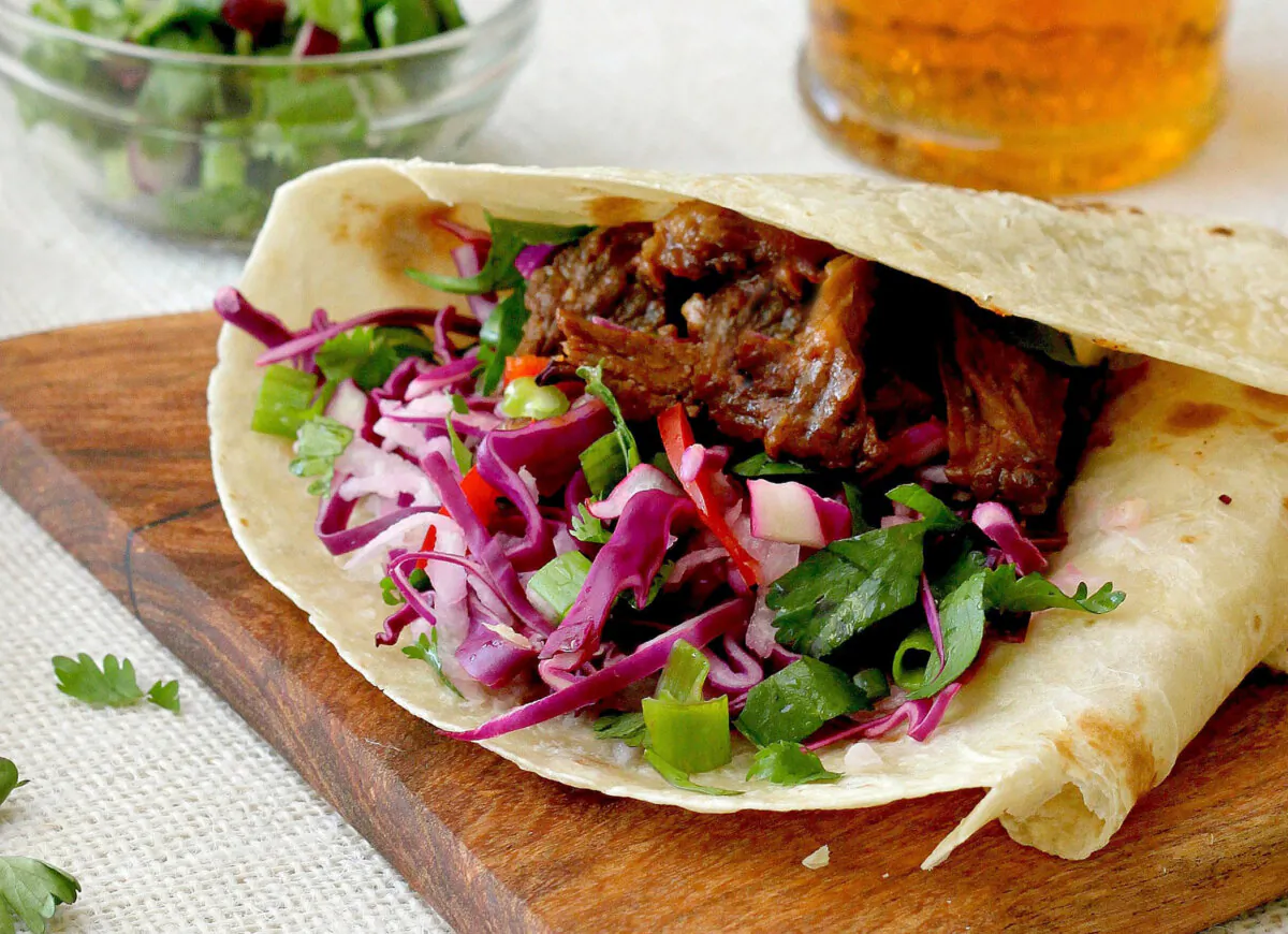 Let everyone assemble their own tacos with spicy, smoky pork; crunchy cabbage slaw; and their favorite fixings. (Lynda Balslev for Tastefood)