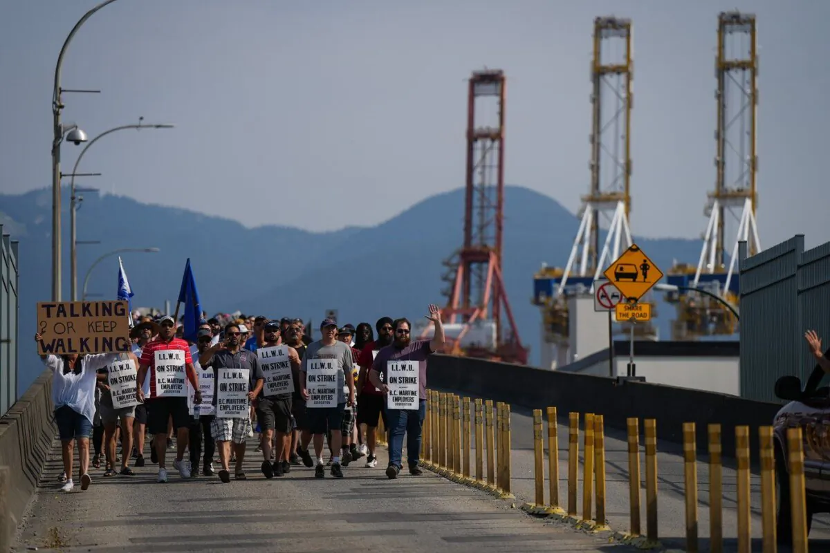 Striking International Longshore and Warehouse Union Canada workers march to a rally as gantry cranes used to load and unload cargo containers from ships sit idle at port, in Vancouver, B.C., July 6, 2023. (The Canadian Press/Darryl Dyck)
