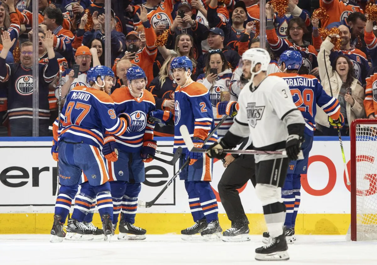 Los Angeles Kings' Matt Roy (3) skates past as Edmonton Oilers' Connor McDavid (97), Zach Hyman (18), Evan Bouchard (2) and Leon Draisaitl (29) as they celebrate a goal during the third period of Game 1 in first-round NHL Stanley Cup playoff hockey action in Edmonton, Alberta, on April 22, 2024. (Jason Franson/The Canadian Press via AP)