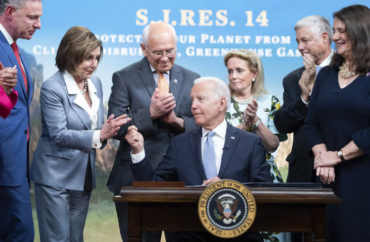 President Joe Biden hands a pen to House Nancy Pelosi (2nd L), alongside other members of the House, after signing a bill dealing with greenhouse gas emissions, in the Eisenhower Executive Office Building, in Washington, on June 30, 2021. (Saul Loeb/AFP/Getty Images)