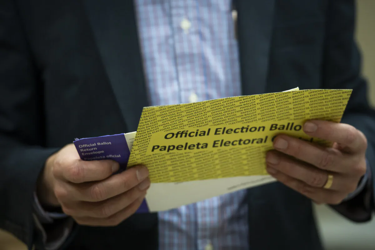 A man holds a mail-in ballot that is ready for scanning at the Lancaster County Government Center in Lancaster, Pa., on April 23, 2024. (Madalina Vasiliu/The Epoch Times)