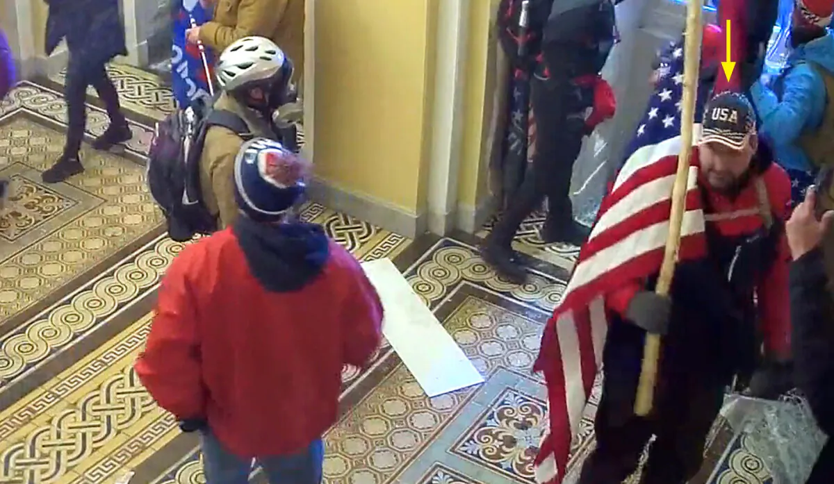 William Pope of Topeka, Kan., carries an American flag just inside the Senate Wing Door at the U.S. Capitol on Jan. 6, 2021. (U.S. Capitol Police/Screenshot via The Epoch Times)