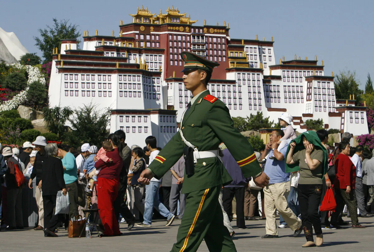 A paramilitary soldier on patrol marches past a crowd gathered in front of a replica of Tibet's most revered landmark Potala Palace, built as an attraction on Tiananmen Square for the National Day holidays, in Beijing on Sept. 26, 2006. (Frederic J. Brown/AFP via Getty Images)