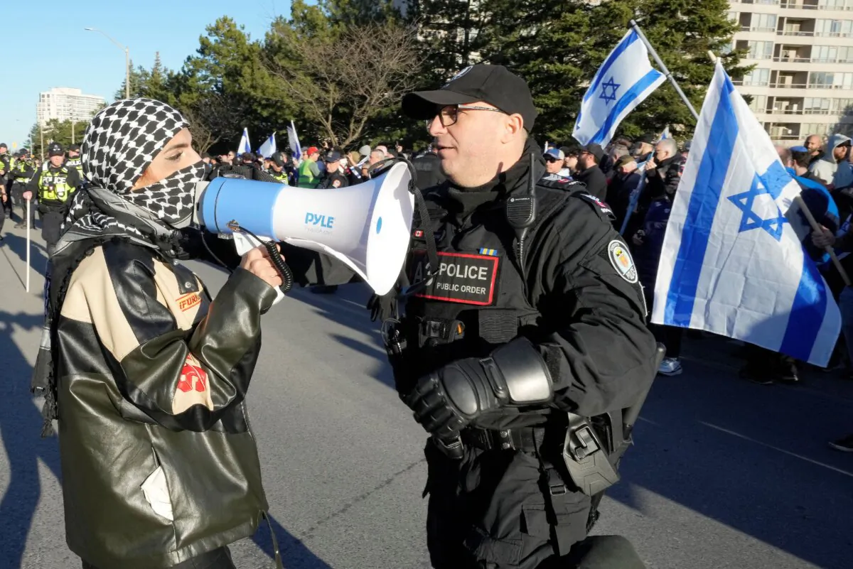 A pro-Palestine protester demonstrating by a synagogue is confronted by a police officer after breaching a line to walk towards pro-Israel protesters in Thornhill, Ont., on March 7, 2024. (The Canadian Press/Frank Gunn)