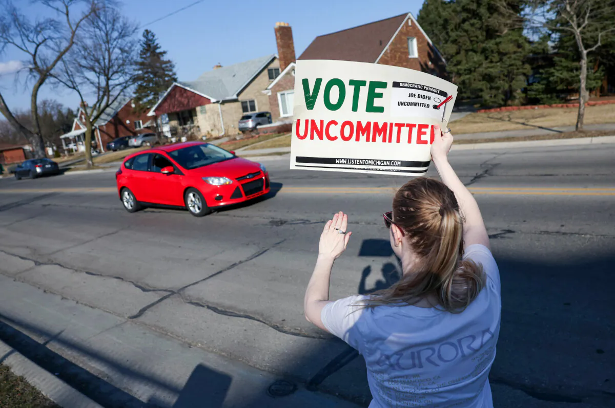 A Democratic voter uncommitted to President Joe Biden rallies outside of a polling location as a car drives past at Oakman Elementary School in Dearborn, Mich., on Feb. 27, 2024. (Kevin Dietsch/Getty Images)