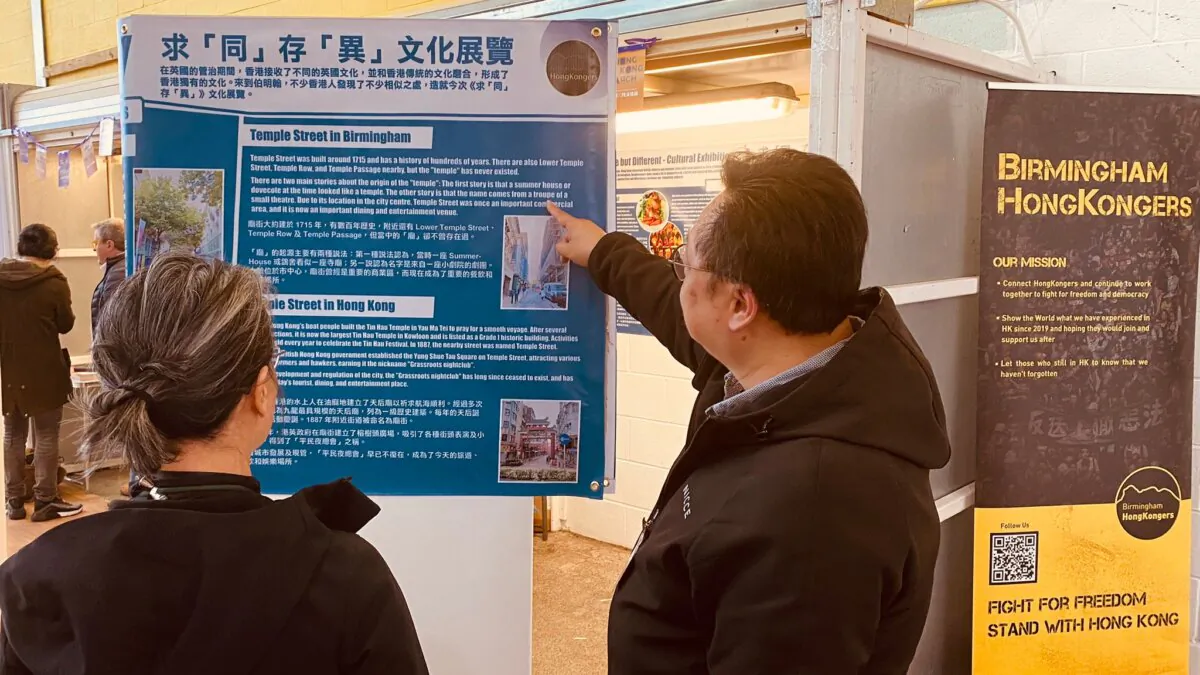 On April 6, Robert (R), person in charge of the Birmingham "Same but Different - Cultural Exhibition" explained the contents on display to visitors. (Bo Dacheng/The Epoch Times)