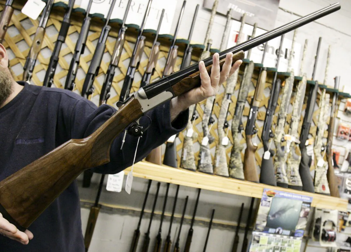 A salesman holds up a rifle at a hunting store in Ottawa, in a file photo. (Jonathan Hayward/The Canadian Press)