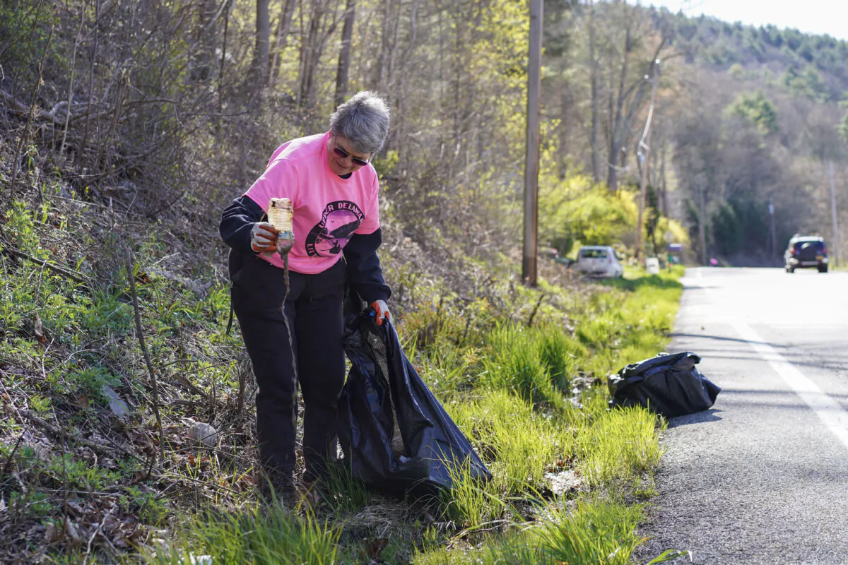 Deerpark resident Virginia Dudko picks up litter along the State Route 97 in Sparrow Bush, N.Y., on April 26, 2024. (Cara Ding/The Epoch Times)