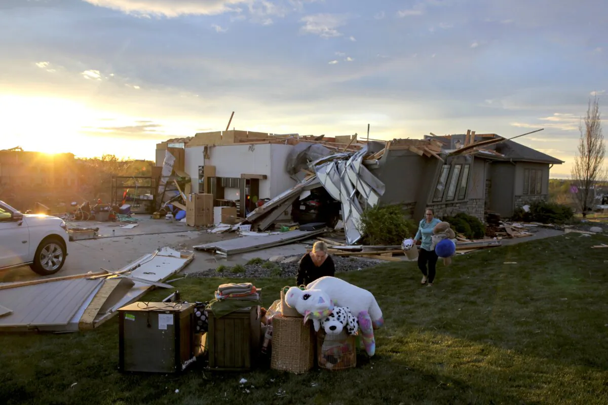 Two women help carry a friend's belongings out of their damaged home after a tornado passed through the area in Bennington, Neb., on April 26, 2024. (Josh Funk /AP Photo)